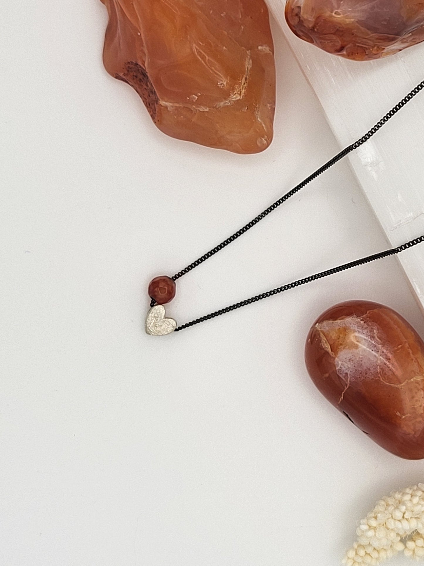 Handgemachte Halskette mit echtem Carneol und Herz aus 925er Silber an oxidierter Kette, minimalistischer Schmuck auf weißem Hintergrund.